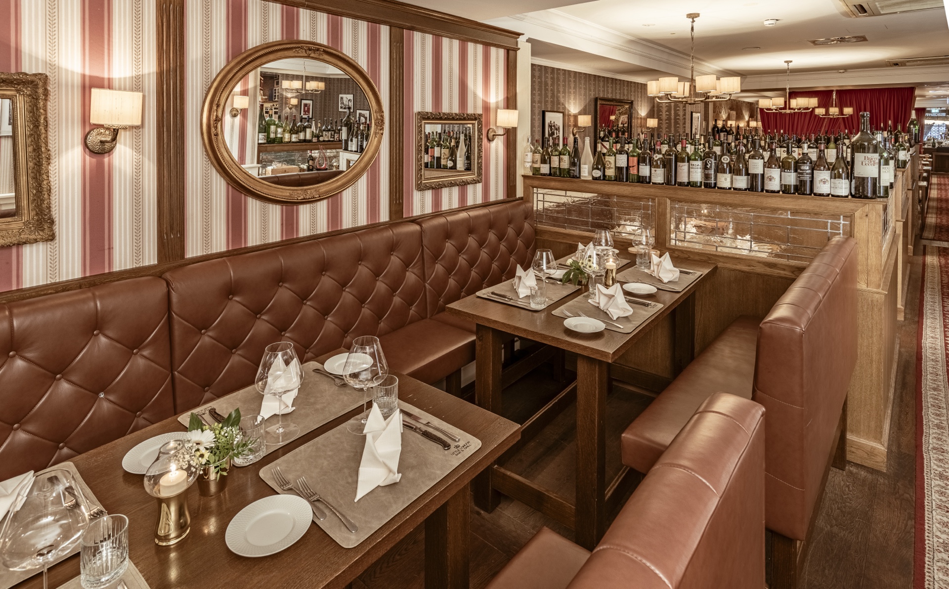 Chesterfield Lounge — Booth mit Weinflaschen-Paravent und Goldspiegel